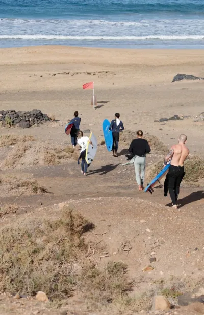 Surfcamp Gruppe läuft mit ihren Surfboards zum Strand auf Fuerteventura