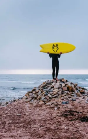 Mann mit Surfboard am Surfspot in Namibia