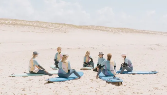 Surfcamp Gruppe kriegt Einführung von Surflehrerin am Strand