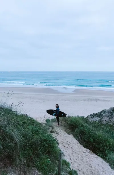 Mann mit Surfboard an einem einsamen Surfspot in Kantabrien
