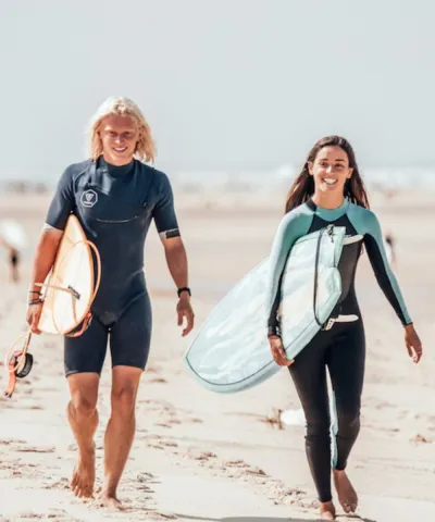 Paar läuft mit Surfboards den Strand in Frankreich entlang