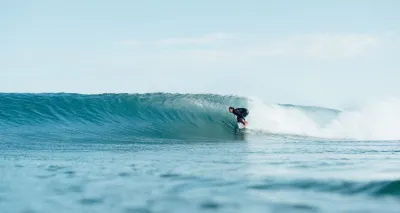 Frau surft perfekte Welle beim Surf-Guiding in Portugal