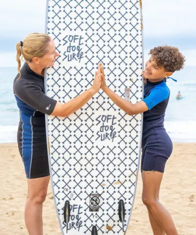 Mutter und Sohn mit Surfboard am Strand in Frankreich