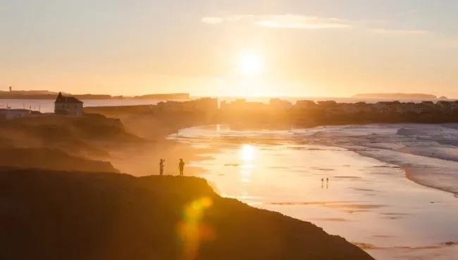 Zwei Menschen beobachten von der Klippe aus den Sonnenuntergang über Baleal