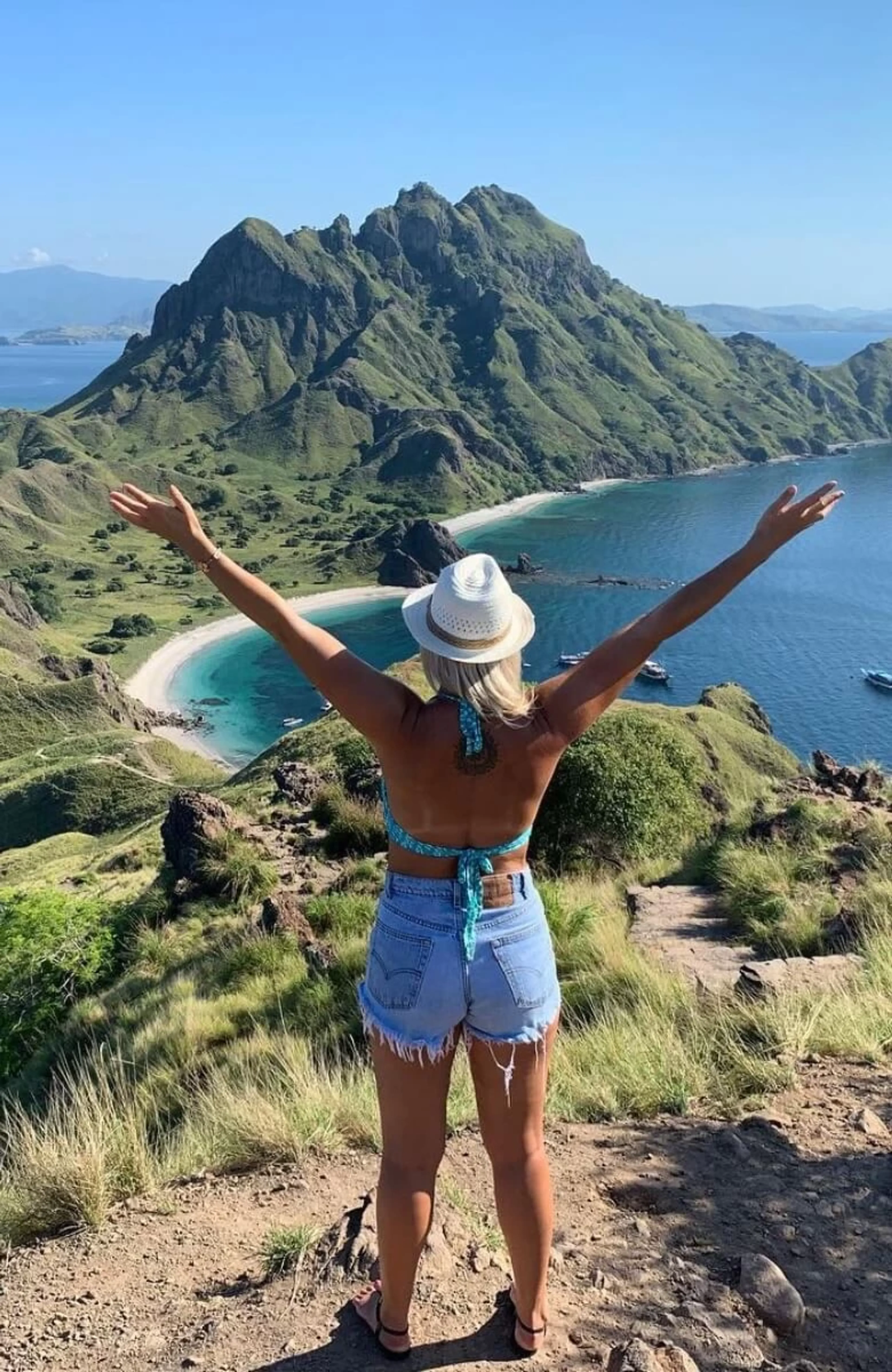 Frau mit hochgestreckten Armen mit Blick auf das Meer