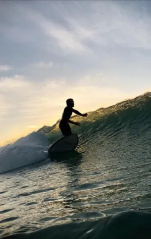 Mann surft Welle bei Sonnenuntergang auf Gran Canaria