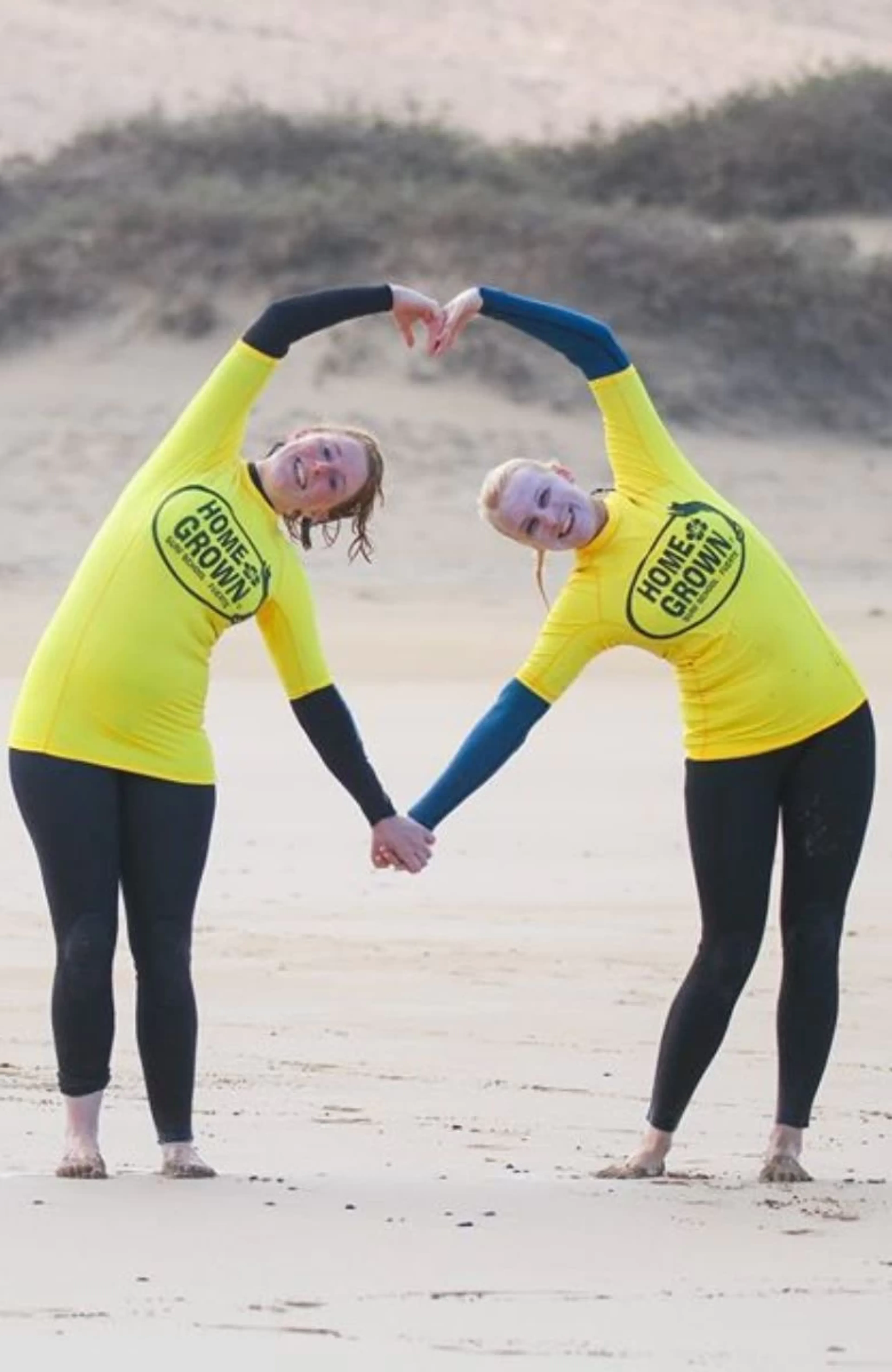 Zwei Freundinnen in Herz-Pose nach der Surf-Einheit am Strand auf Fuerteventura