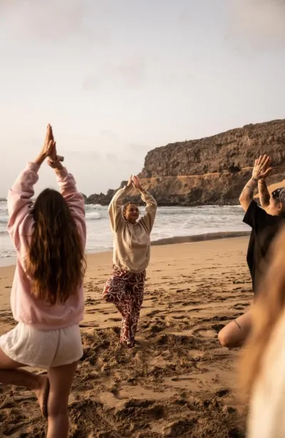 Gruppe in Tree-Pose bei Yoga Einheit am Strand auf Fuerteventura