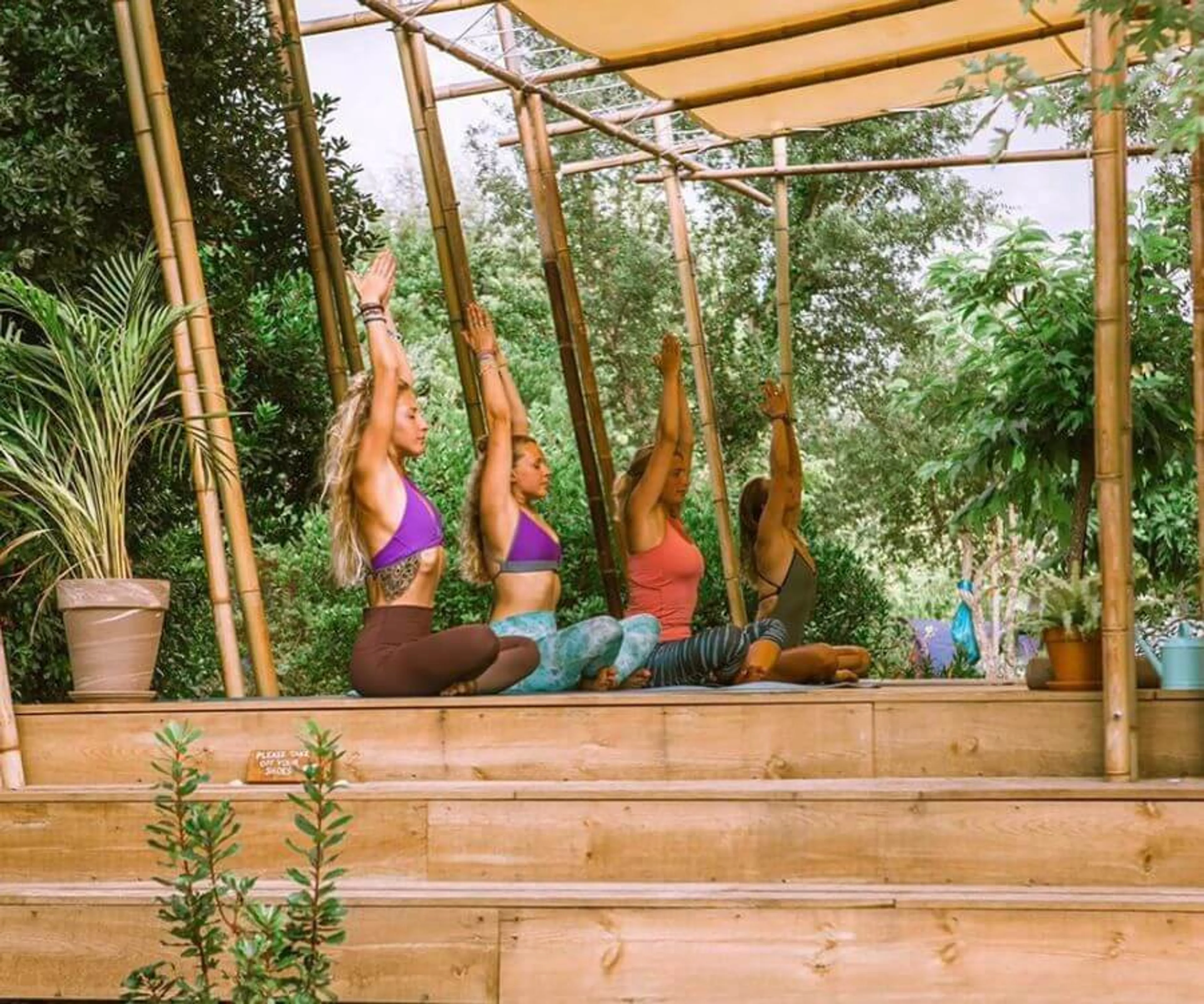 Gruppe bei Yoga-Einheit draußen in der Natur auf der Yoga-Plattform