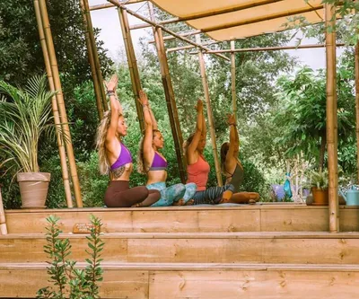 Gruppe bei Yoga-Einheit draußen in der Natur auf der Yoga-Plattform